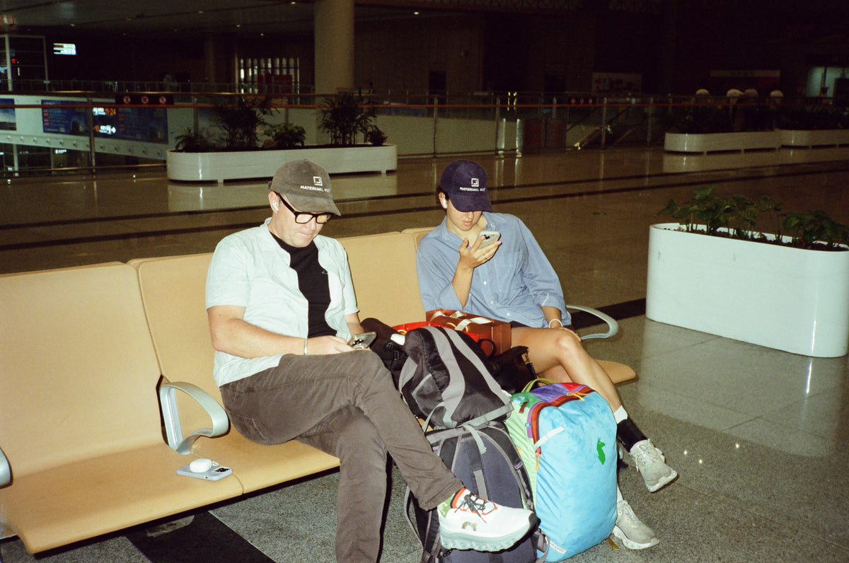 Waiting in an airport with travel bags and Materiaal Post caps.