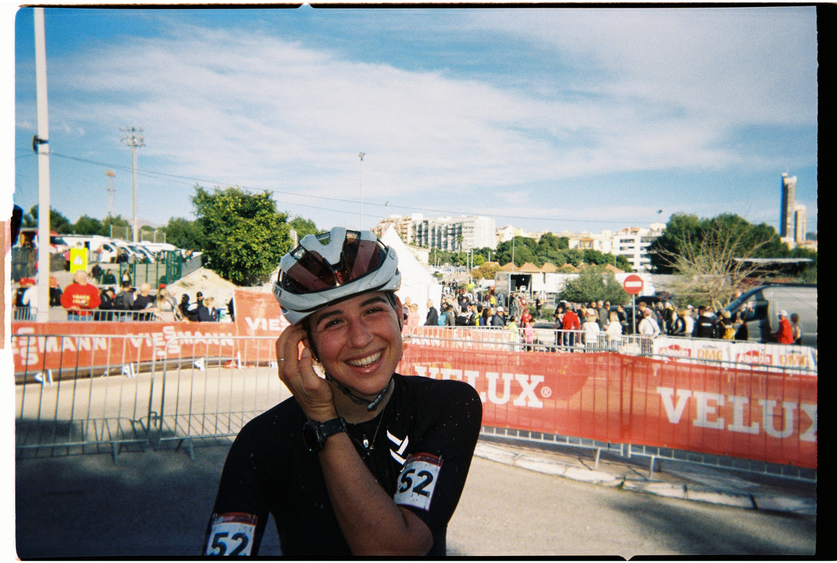 A smiling cyclist in a helmet beside the course barriers on race day.