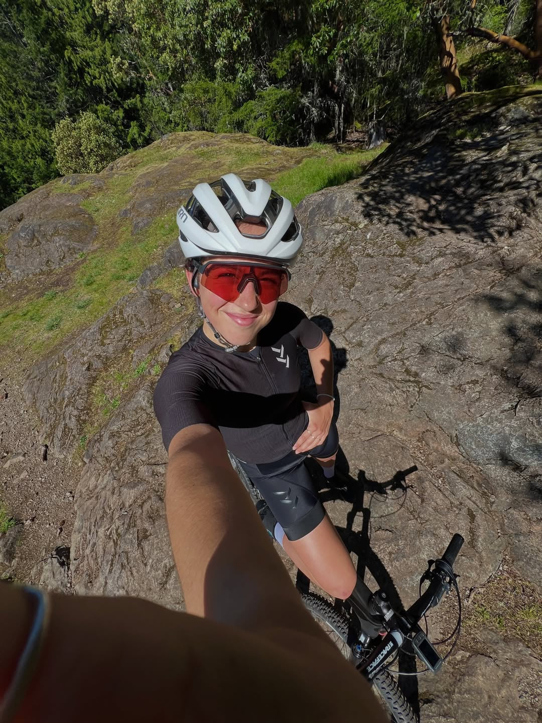 Sidney McGill taking a selfie in her cycling kit on a rocky trail.