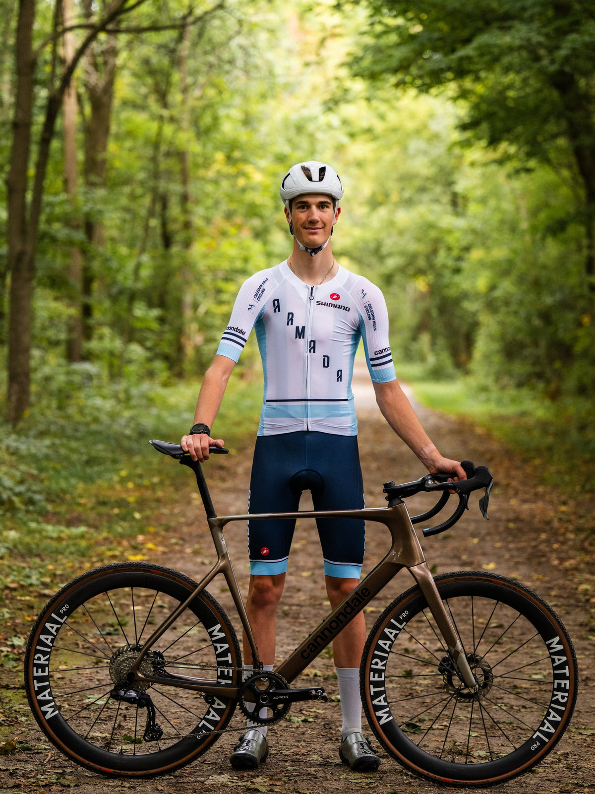 Rhett Bates with his bike and Materiaal wheels on a wooded trail.